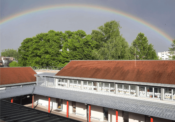 Un arc en ciel au dessus des toits de l'école privé maternelle et primaire Saint Vincent, située à Ferney Voltaire, dans le Pays de Gex